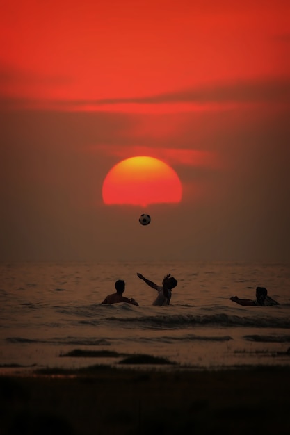 Foto i ragazzi stanno giocando al tramonto nel mare