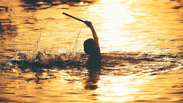 The boys are playing the water in the sunset