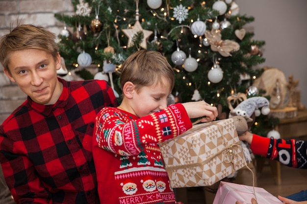 Ragazzi fratelli con regali all'albero di natale nel soggiorno decorato a festa, concetto di capodanno