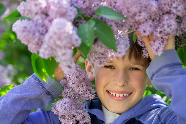 Foto un viso di ragazzo in fiori di lilac primaverile bambino in una passeggiata primaverile la primavera è arrivata