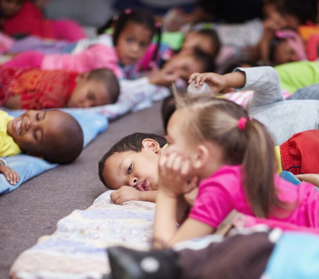 Boys and girls lying on floor in nursery school