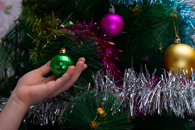 Boys hand decorating christmas tree with toys