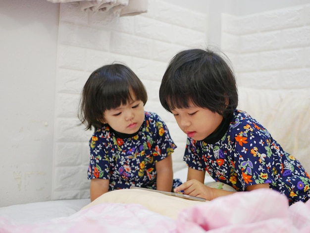 Photo boys looking away while standing on bed