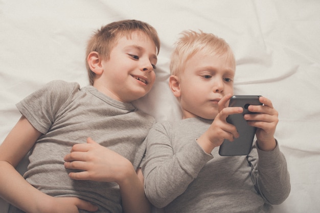 boys lying in bed with a smartphone