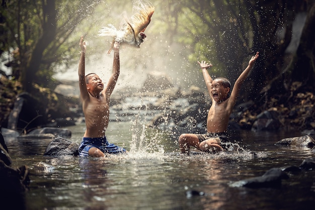 Boys playing with their duck in the creek