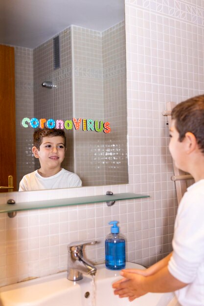 Boys washing hands while looking in mirror