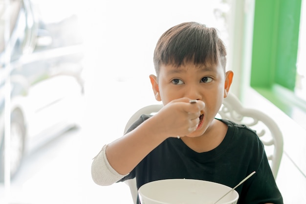 상처 입은 손에있는 아이들이 혼자 밥을 먹는다.