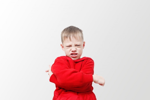 Boze agressieve verontwaardigde jongen. Kind in een rode hoodie drukt woede uit. Opwinding en frons. Stress, autisme. Verstoor frustratie en onheil