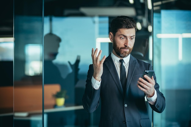 Boze en nerveuze baas die in telefoon schreeuwt tijdens telefoongesprek met werknemer zakenman in modern kantoor met telefoon