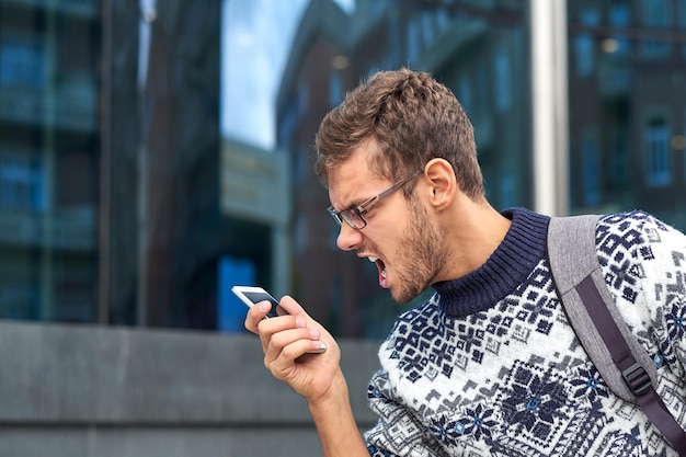 Boze jonge man die aan de telefoon schreeuwt