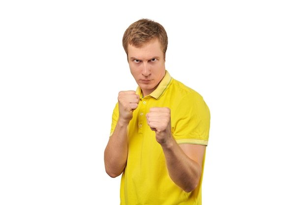 Boze jonge man in gele tshirt klaar om te vechten met vuisten geïsoleerd op een witte achtergrond