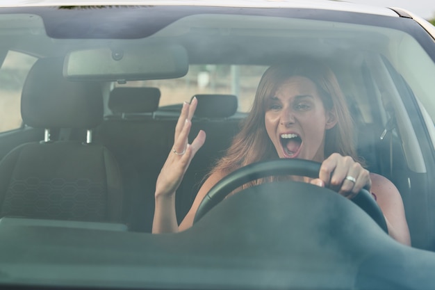 Boze jonge mooie vrouw in haar auto tijdens het rijden. Verkeersveiligheidsconcept