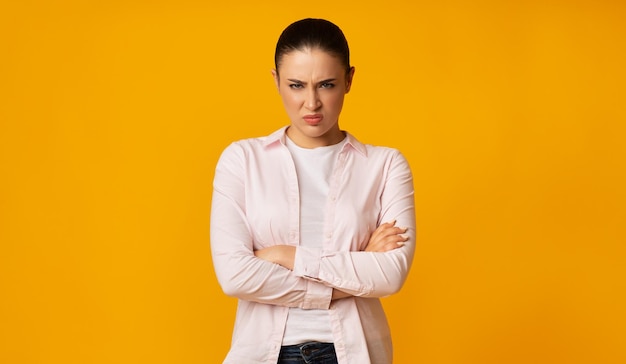 Boze Jonge Vrouw Fronsend Handen Kruisen Op Gele Achtergrond