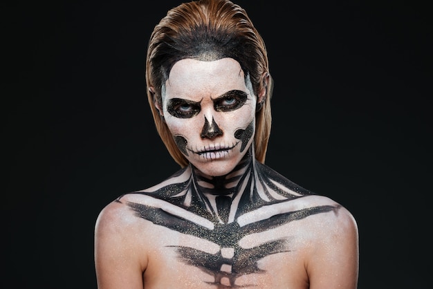 Boze jonge vrouw met gotische halloween-make-up over zwarte achtergrond