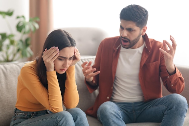 Boze moslimman die vrouw schreeuwt die thuis op de bank zit