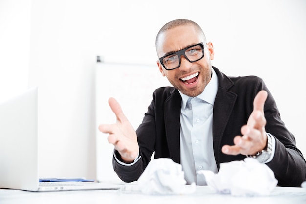 Boze nerveuze zakenman die aan het bureau werkt, overladen met papierwerk en schreeuwend naar de camera