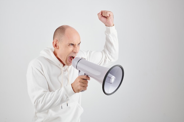 Boze volwassen man in witte hoodie schreeuwt in megafoon en eist gerechtigheid