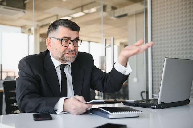 Boze zakenman die met document tegen iemand schreeuwt