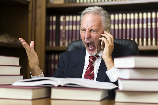 Boze zakenman die op cellphone schreeuwt terwijl het lezen van een boek