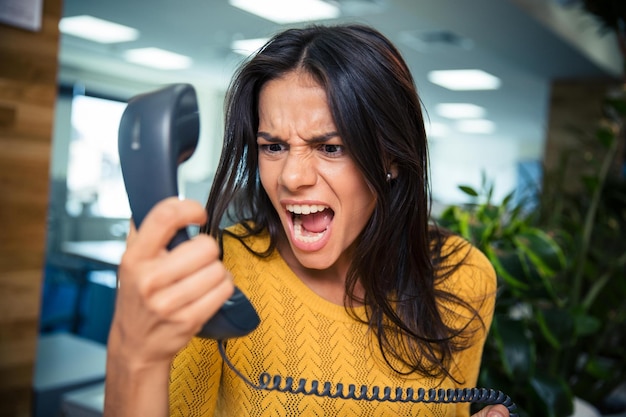 Boze zakenvrouw schreeuwen op telefoon in kantoor