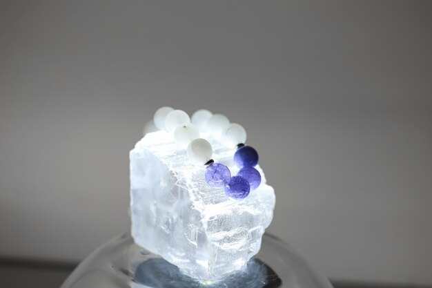 Photo a bracelet made of natural stones of different colors lies on a large transparent stone