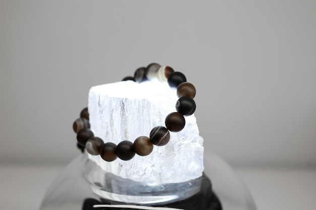 A bracelet made of natural stones of different colors lies on a large transparent stone