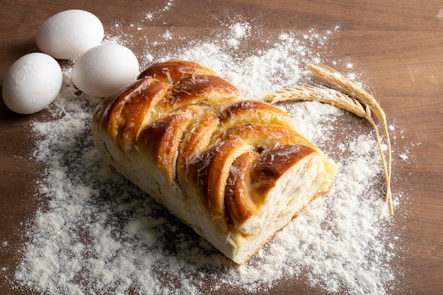 Braided bread decorated with grated coconut, eggs and wheat branch,