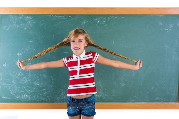 Ragazza bionda dello studente intrecciato che gioca con le trecce