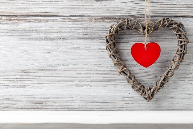 Photo braided wicker heart with a red heart in the middle on a wooden background