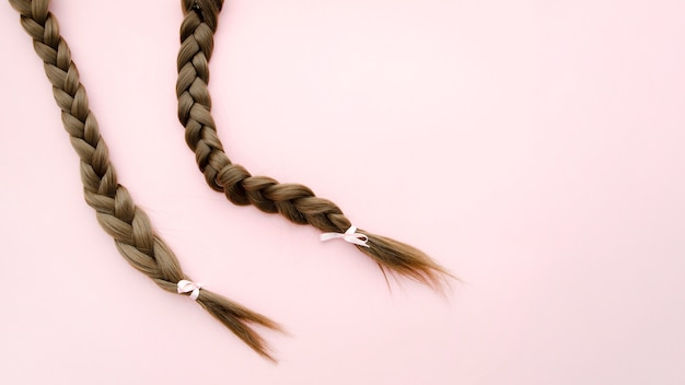 Photo braids with ribbons on pink background