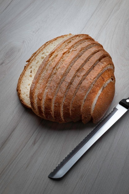 Мозговой хлеб, нарезанный ломтиками ножом на сером столе