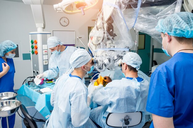 Brain surgery. Group of surgeons in operating room with surgery equipment.