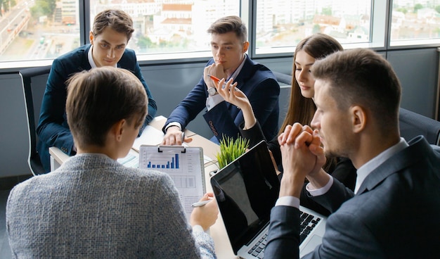 Brainstorm Groep zakenmensen die samen naar de laptop kijken Een zakenvrouw die naar de camera kijkt