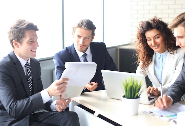 Brainstorm. group of business people looking at the laptop\
together. one business woman looking at camera.