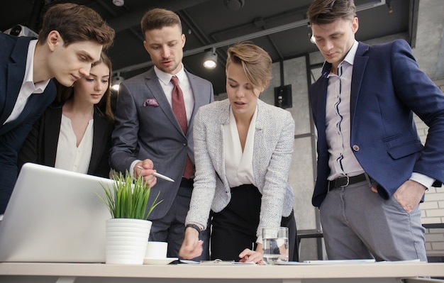 Brainstorm. Group of business people looking at the laptop together.