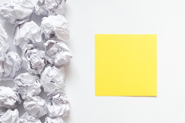 Brainstorming concept Flat lay of crumpled paper ball pile and yellow black note on white background Copy space