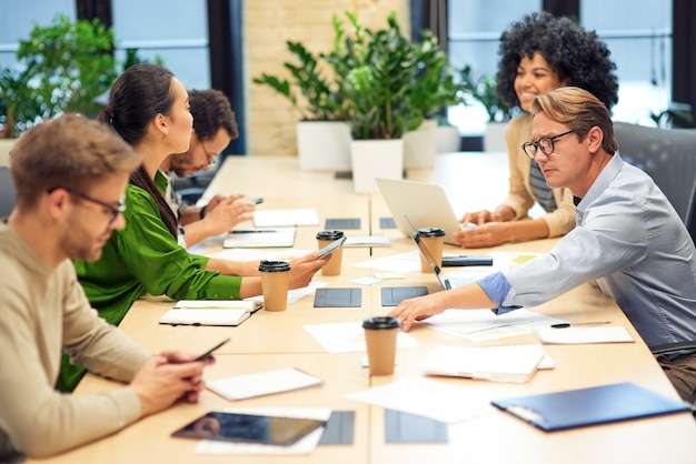 Photo brainstorming meeting. group of multiracial colleagues sitting in board room in the modern office and working together. teamwork and collaboration concept