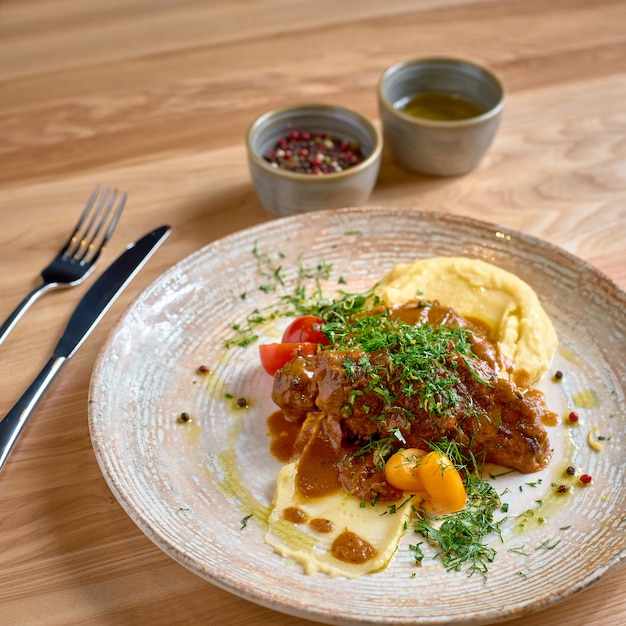 Braised Beef cheeks in brown sauce with mushroom and mashed potatoes as closeup on a modern design plate