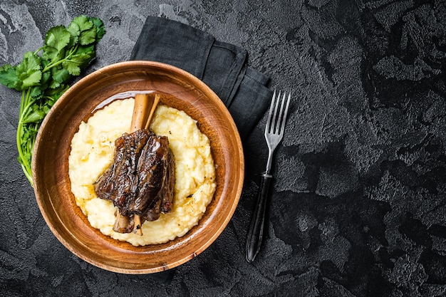 Braised lamb shank on the mashed potato in a plate black background top view copy space