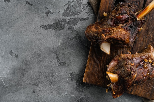 Braised Lamb Shanks with Sauce and Herbs set on gray stone table background top view flat lay with copy space for text