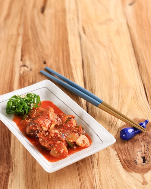 Braised Mackerel or Godeungeo Jorim, One Various of Korean Side Dish Banchan for Lunch or Dinner, Served on Wooden Table, White Plate. Copy Space for Text