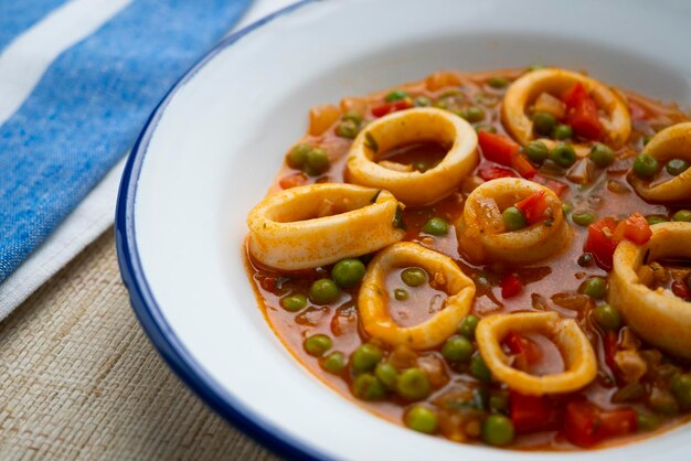 Foto anelli di calamari brasati con pomodoro e verdure. ricetta tradizionale spagnola della tapa.