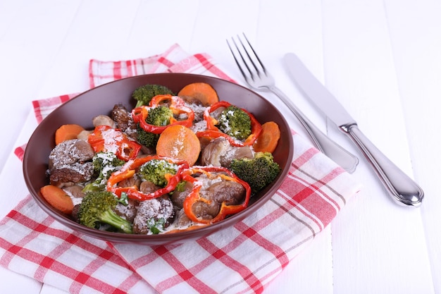 Braised wild mushrooms with vegetables and sauce in plate on table