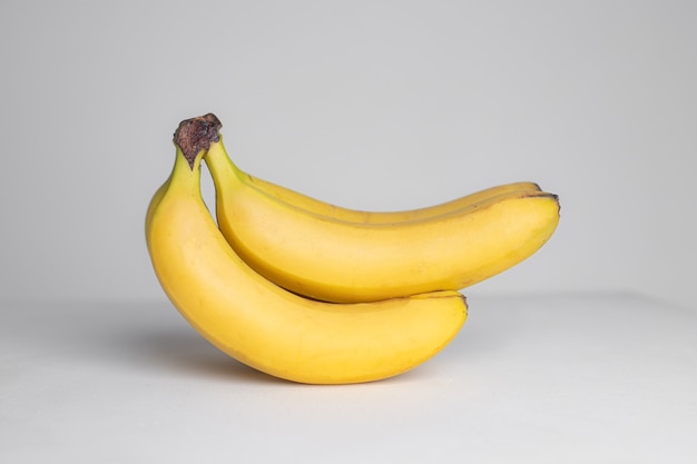 A branch of bananas on a gray wall . Fruit. Exotic fruit. Fruit in the studio. Copy space
