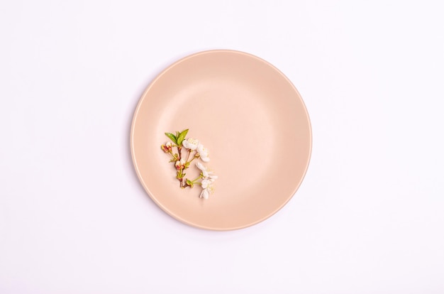 Photo a branch of cherries on a beige plate on a white background. flat lay, copy space, march 8, mother's day, banner. view from above