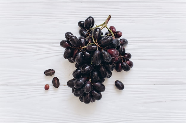 Photo a branch of dark grapes on a white table, top view and flat lay.