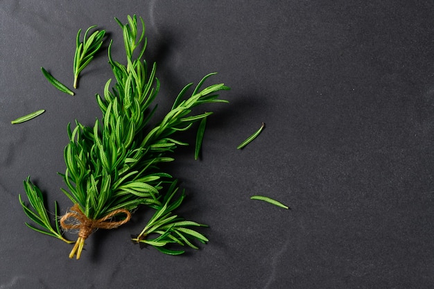 Branch of fresh rosemary on black table background.