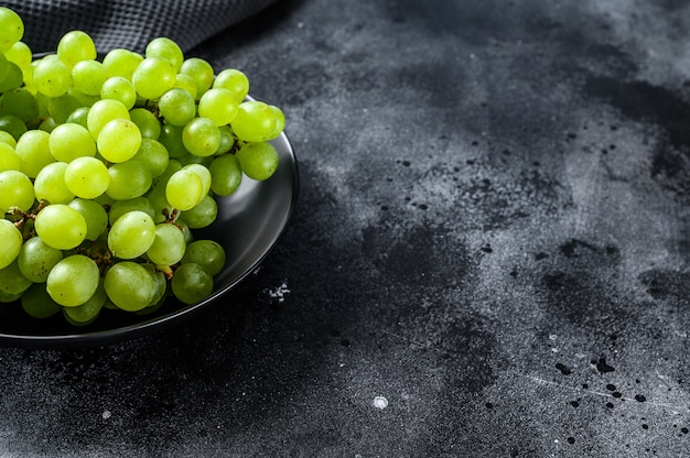 A branch of green juicy grapes in a plate