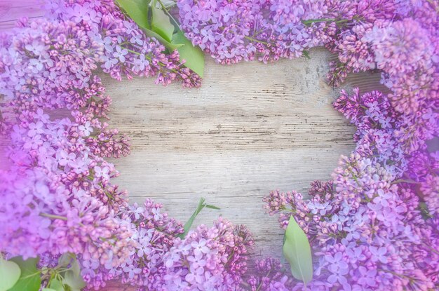 Branch of lilac flowers on wooden table Frame made from lilac flowers