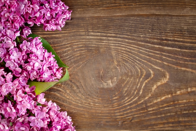 Branch of lilac lying on a brown wooden background.